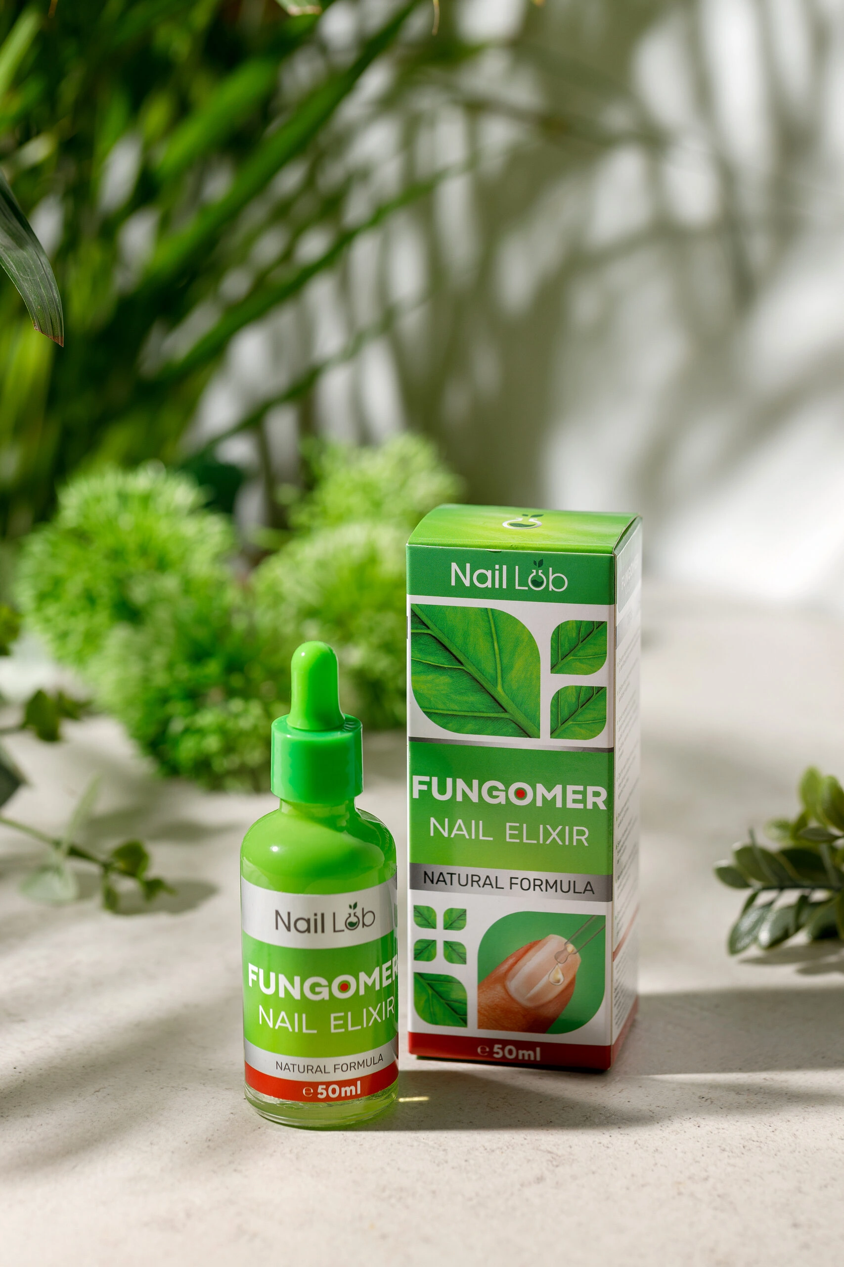 Fungomer Nail Elixir 50ml bottle and packaging featuring natural formula for nail care, showcased with greenery in the background